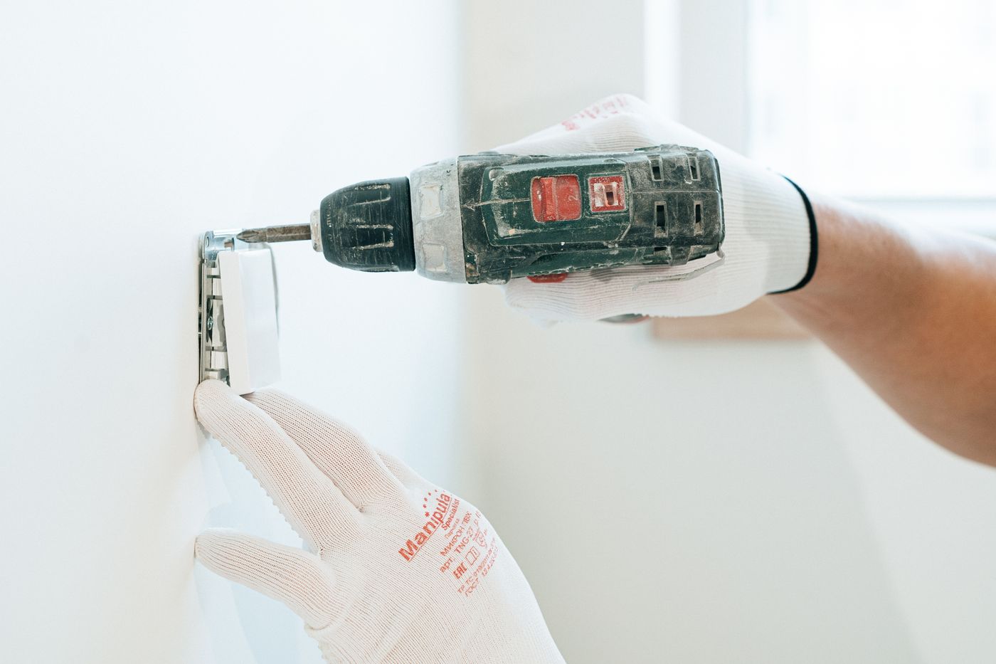 Électricien fixant un boîtier au mur